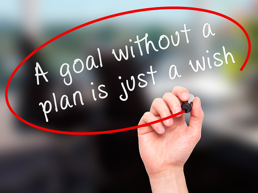 Man Hand writing "A goal without a plan is just a wish" black marker on visual screen.  Business, technology, internet concept.